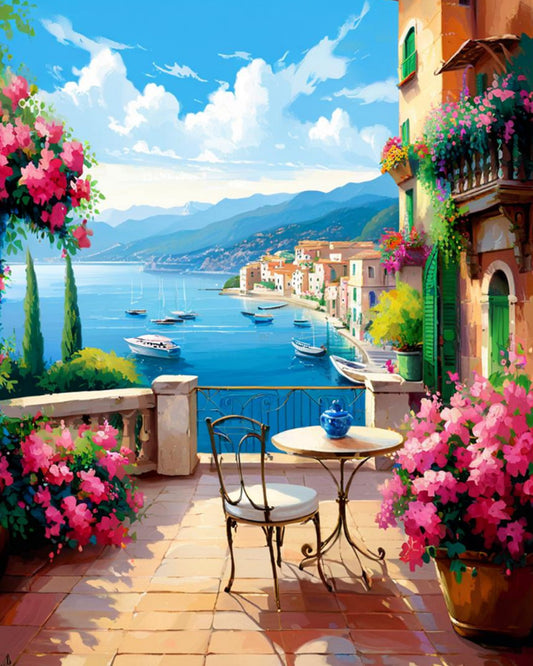 Cozy outdoor seating area with flowers and a view of a coastal town and mountains.
