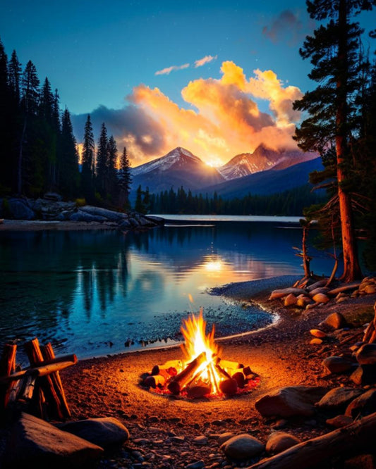 Campfire by a lake with mountains and sunset in the background