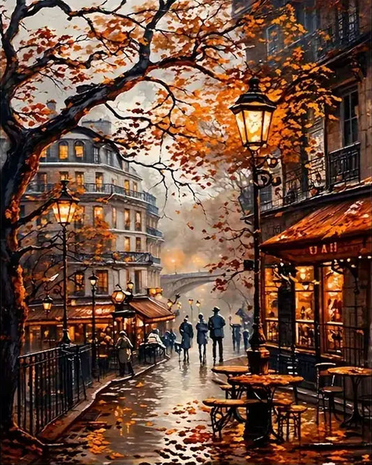 A warm-toned city street scene painting with autumn trees, glowing street lamps, café tables and chairs, pedestrians, and buildings with lit windows. 